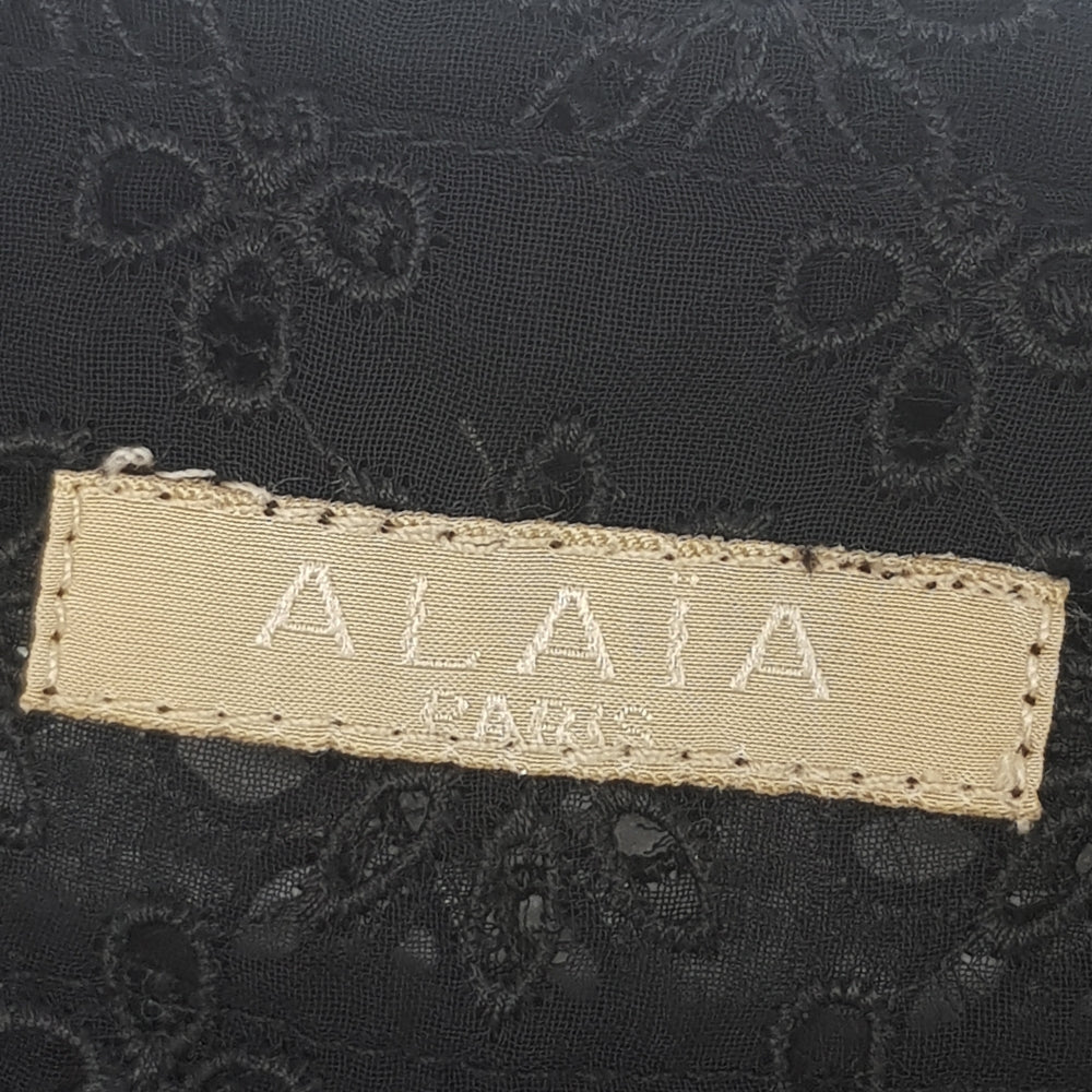 Black sheer broderie blouse by Alaïa, featuring delicate embroidery and a lightweight, elegant top design.