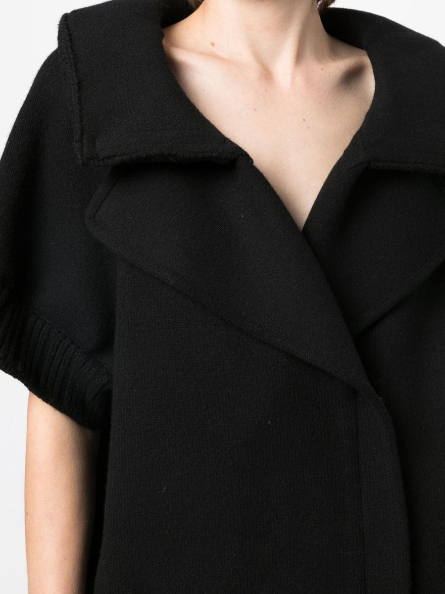 Black Chanel short-sleeved knit gilet, stylish blazer or jacket, featuring a sleek design and textured fabric.