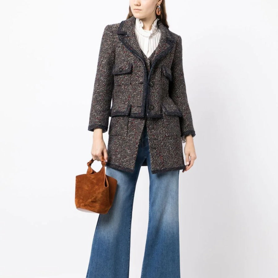 Chanel layered tweed blazer with classic collar, front buttons, and textured fabric, stylishly displayed on a hanger.