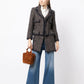 Chanel layered tweed blazer with classic collar, front buttons, and textured fabric, stylishly displayed on a hanger.