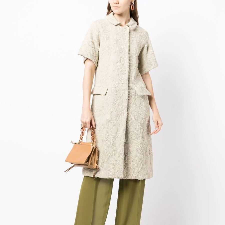 Bottega Veneta light beige short-sleeved jacquard coat with textured woven pattern, rounded collar, concealed fastening and flap pockets.