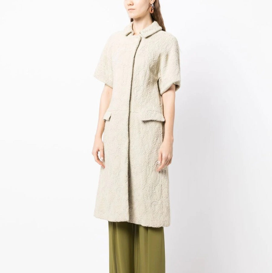 Bottega Veneta light beige short-sleeved jacquard coat with textured woven pattern, rounded collar, concealed fastening and flap pockets.